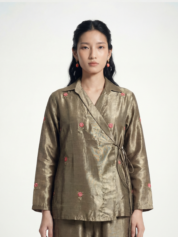 Female model wearing VUNN Copper Tissue Wrap Shirt — copper-gold tissue silk wrap shirt with rose-pink hand-embroidered booti motifs, notched lapel and side-tie closure