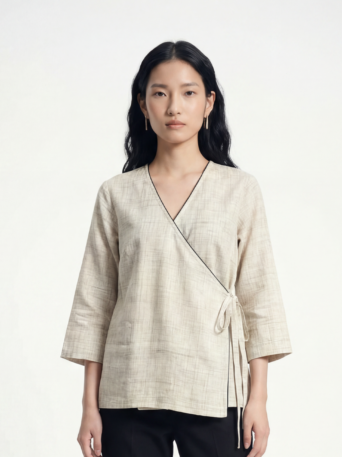 Female model wearing VUNN Ivory Handloom Wrap Top — ivory handloom cotton wrap with V-neckline, side-tie closure, black piping detail and three-quarter sleeves