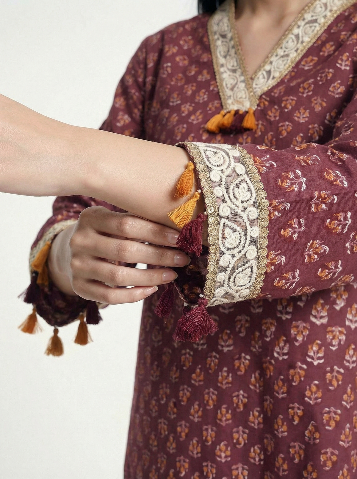 Female model wearing VUNN Kaashi Kurta — deep maroon hand-block printed cotton kurta with ochre florals, ivory gota-lace V-neck, tassel-trimmed sleeves and matching printed pants