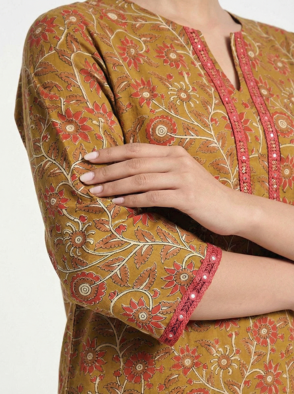 Female model wearing VUNN Taruja Kurta — mustard ochre hand-block printed cotton kurta with coral floral jaal, pink gota-lace V-neckline and mirror sequin sleeve detail