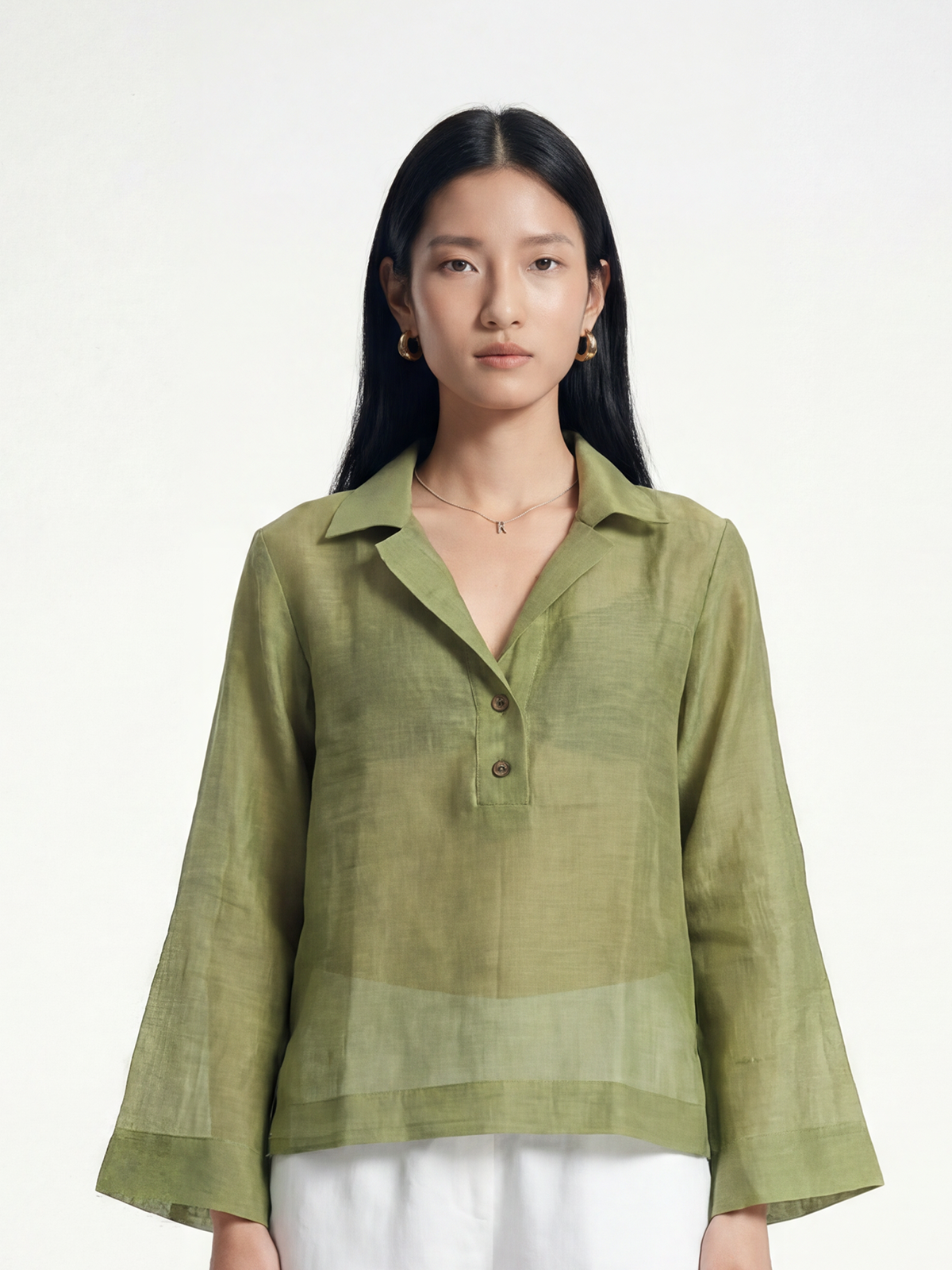Female model wearing VUNN Moss Linen Popover — moss-green semi-sheer linen popover with a camp collar, short button placket and long flared sleeves